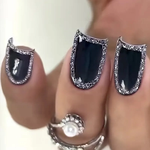 Macro detail of glossy black press-on nails with silver glitter edges and a vintage ring