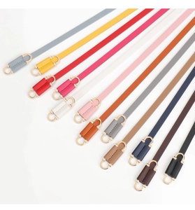 Colorful set of slim leather belts with gold buckles arranged diagonally on white