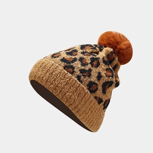 Detailed view of leopard print knit beanie with a brown faux fur pom pom on top