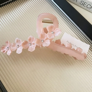 Gros plan sur une pince à cheveux fleur rose en résine avec strass sur un plateau