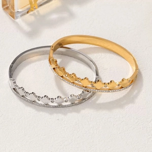Elegant gold and silver crown bracelets with zircon inlay on a white textured surface
