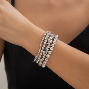 Close-up of silver metal beaded bracelets stacked on model wrist for a layered look