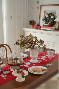 Detail of red Christmas table runner with candy jacquard and wooden cake stand display