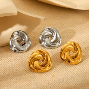 Close-up of twisted knot earrings in gold and silver finish with metallic shine
