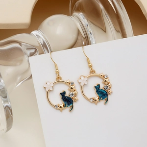 Detailed close-up of kitty earrings with star and moon charms on a golden base