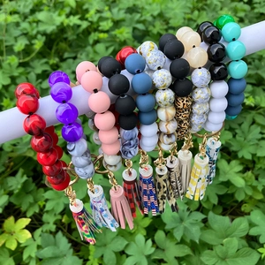 Colorful silicone bead bracelet keychains with tassels displayed on a green plant background