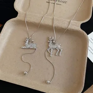Elegant silver reindeer pendant necklaces with white crystals on a rustic textured background