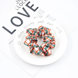 Detail of red and green plaid Christmas scrunchie on minimalist white ceramic plate