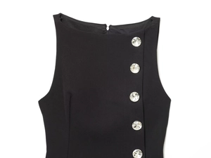 Detail view of round crystal buttons on a black sleeveless top with a neat round neckline