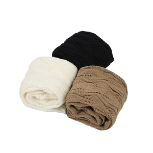 Three rolled pairs of cable knit leg warmers in black, beige, and camel brown colors