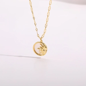 Macro detail of 14K gold plated sun and moon pendant with shimmering white inlay