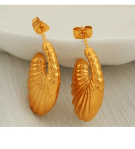 Macro shot of gold-plated twisted earrings featuring vintage ribbed texture and metallic shine