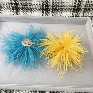 Detail of light blue and yellow ostrich feather brooches with dual-purpose metal clips