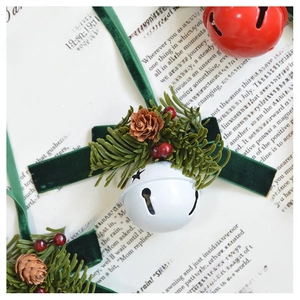 Detail of Christmas bell with star cutout, green velvet ribbon, and pine cone decor