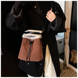 Brown suede bucket bag with white faux fur trim shown as cross-body style on model