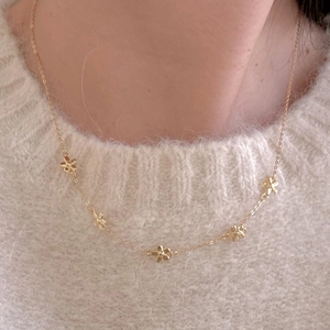 Elegant 925 sterling silver gold floral necklace worn by a model on a white sweater