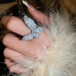 Close-up of sparkling zircon butterfly ring on hand with elegant white feather sleeve detail