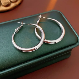 Polished silver hoop earrings displayed on a dark green leather jewelry box