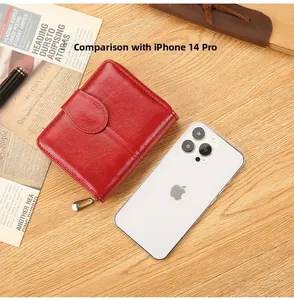 Short red leather wallet size comparison with iPhone 14 Pro on a wooden desk surface