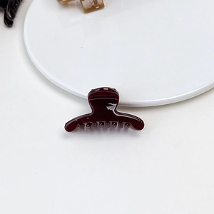 Close-up of a small burgundy jelly hair claw clip showing glossy acrylic texture and finish