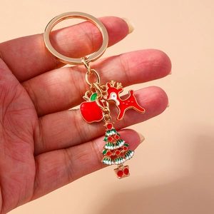 Close-up of metal Christmas keychain with enamel reindeer, apple and tree pendants