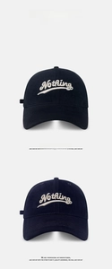 Detail of Nothing embroidery on black and navy blue cotton twill baseball caps