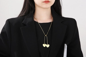 Close-up of a gold heart pendant Y-necklace worn on a black blazer for a stylish look