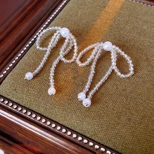Detailed close-up of bow earrings with crystal beads and pearls on a vintage box
