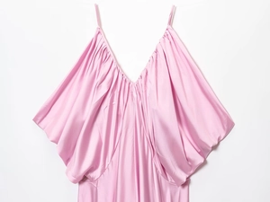 Detail of silk satin fabric texture and elegant draping on pink V-neck slip dress
