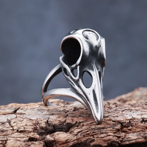 Macro shot of Viking crow skull ring on natural wood bark with vintage silver finish