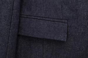 Detail of dark blue denim jacket pocket with contrast stitching and snow-washed texture