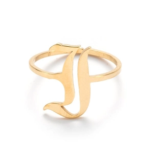 Macro detail of gothic style letter J gold plated stainless steel ring on white background