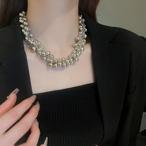 Detail shot of a layered silver ball choker necklace worn with a black suit blazer