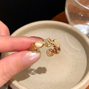 Close-up of golden vintage镂空 ring with cat-eye stones on a rustic ceramic bowl