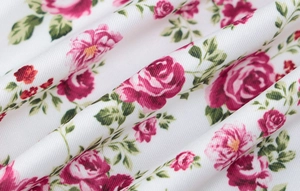Close-up detail of soft floral fabric with red roses and green leaves pattern