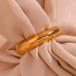 Close-up of a polished 18K gold plated chunky ring on soft pleated pink silk fabric