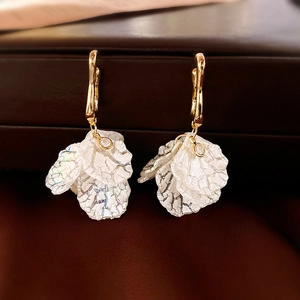Detailed macro view of white acrylic floral earrings with golden hooks and zircon accent