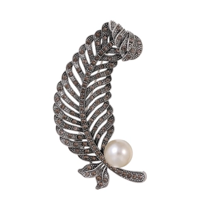 Detailed close-up of retro silver feather brooch with brown rhinestones and white pearl