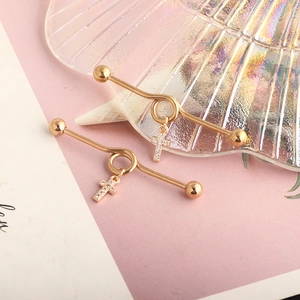 Detail of golden industrial barbell with sparkling cross pendant on shell background