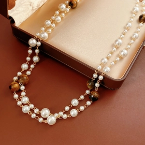 Close-up of double-layer necklace with white pearls and brown tiger eye beads on leather