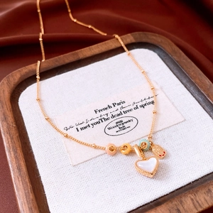 Detail view of 18k gold heart pendant with colored beads and satellite chain