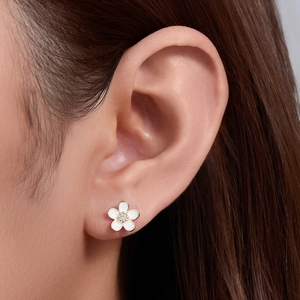 Elegant white five-petal flower stud earrings with gold trim and crystal center on ear