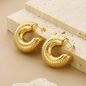 Detailed view of gold hollow C-shaped earrings with wave texture on stone base