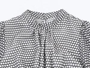 Detail showing high-quality neckline stitching and back button closure on polka dot dress