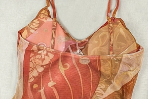 Dettaglio dell'abito in mesh con stampa astratta arancione, scollo a V e spalline fini
