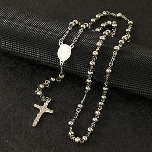Macro view of silver bead chain necklace featuring Saint Benedict medal and crucifix