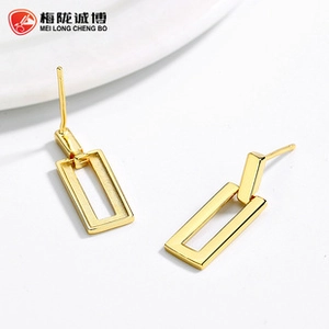 Detailed close-up of geometric rectangular gold earrings on a clean white surface