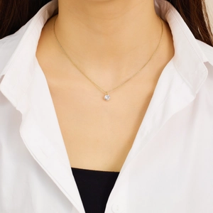 Close-up of a delicate gold chain necklace with a sparkling round diamond pendant on a model