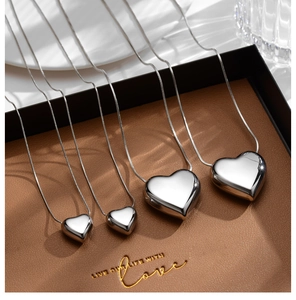 Detailed comparison of four polished silver heart necklaces in various sizes on leather