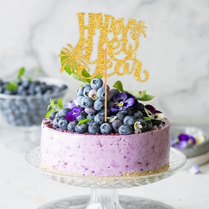Décoration de gâteau dorée Happy New Year avec paillettes sur cheesecake aux bleuets